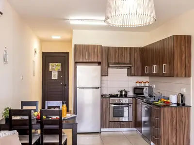 a kitchen with wooden cabinets and a white refrigerator at Mythical Resort by KARMA in Paralimni