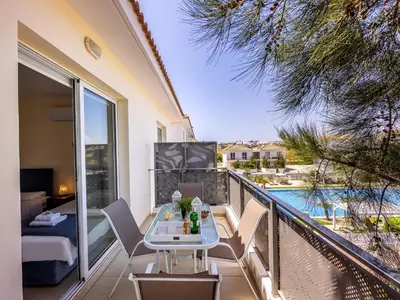 a balcony with a table and chairs and a pool at Mythical Resort by KARMA in Paralimni