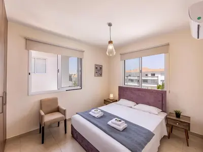 a bedroom with a bed and a chair and windows at Mythical Resort by KARMA in Paralimni