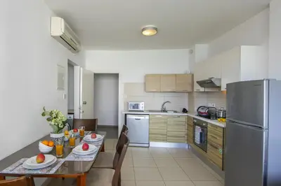 a kitchen with a table and a stainless steel refrigerator at Coralli A 305 in Protaras