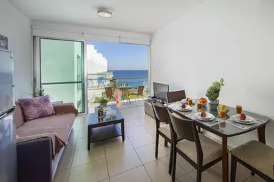 a living room with a dining table and a view of the ocean at Coralli A 305 in Protaras