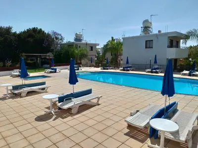 a pool with chairs and tables and umbrellas at Constantaras Apartments in Protaras