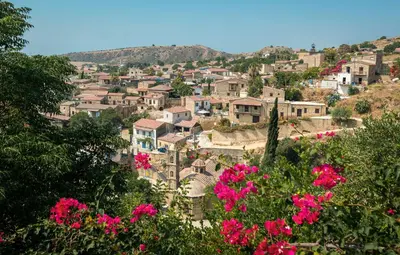 a village on a hill with pink flowers at The Carob Tree Villa - Rustic Luxury Home With Access To Pool And Restaurant in Larnaka