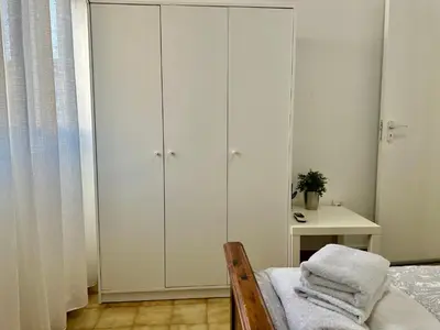 a bedroom with white cabinets and a bed and a table at Tsimintia Apt 25 in Larnaka