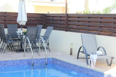 a patio with chairs and a table and a pool at Natali villa in a perfect location in Paralimni