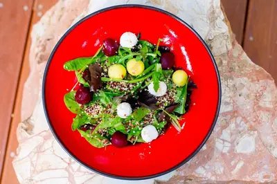 a red plate with a salad on a table at Hotel Indigo Larnaca by IHG-ADULTS ONLY in Larnaka