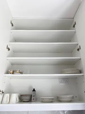 a white kitchen with white shelves and plates at Cozy place in Larnaka