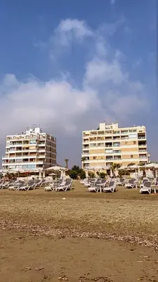 two buildings and lounge chairs on the beach at Cozy place in Larnaka