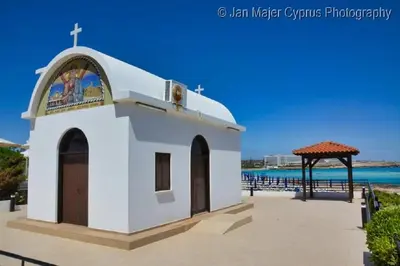 a small chapel on the beach with the ocean in the background at Nissi Golden Sands Holiday Apartment Free WiFi in Ayia Napa