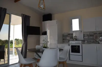 a kitchen with white cabinets and a table and chairs at MERSINERA Paradise Garden 2 in Larnaka
