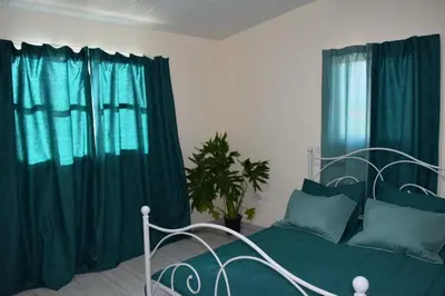 a bedroom with a green bed with blue curtains at MERSINERA Paradise Garden 2 in Larnaka