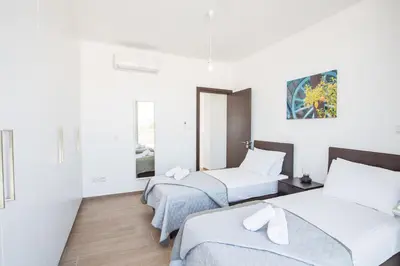 two beds in a room with white walls at Protaras Olivine Villa OL17 in Protaras