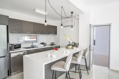 a kitchen with a white counter and stools at Olivine 3 Bedroom Villas in Protaras