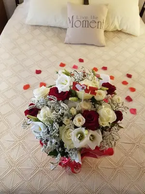 a bouquet of red and white flowers on a bed at Irene's House in Kakopetria