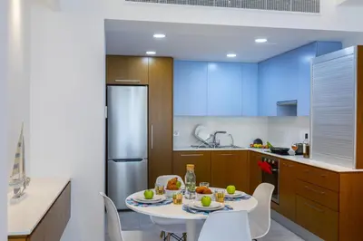 a kitchen with a white table and white chairs at Mackenzie Castella Beachfront Suite in Larnaka