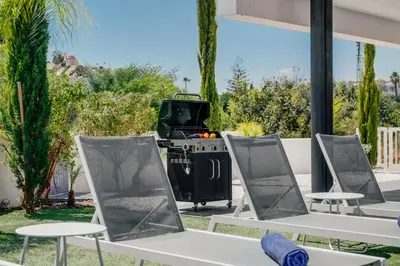 a group of tables and chairs with a tv in a yard at Protaras Olivia Pearl Villa in Paralimni