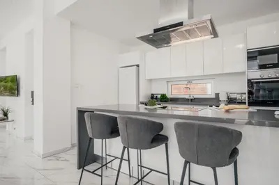 a kitchen with a counter with three bar stools at Protaras Olivia Pearl Villa in Paralimni