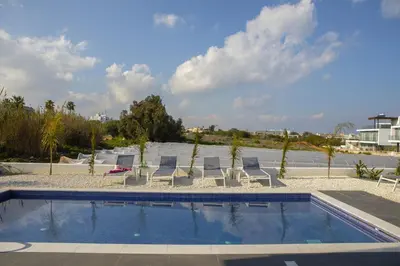 a pool with chaise lounge chairs and a swimming pool at Protaras Olivine Pearl in Protaras
