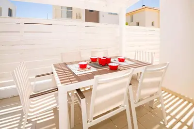 a table with white chairs and red cups on it at Villa Blue Sky in Protaras