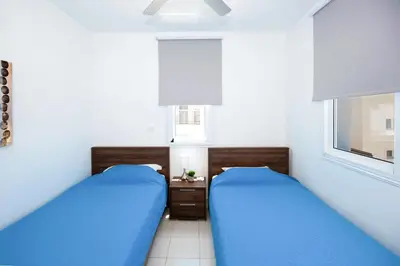 two beds in a bedroom with blue sheets and a window at Villa Blue Sky in Protaras
