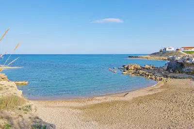 a beach with rocks and the ocean on a clear day at Villa Caren in Paralimni