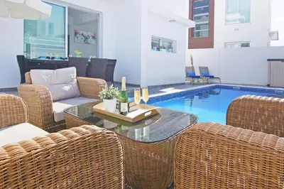 a patio with wicker chairs and a table and a pool at Villa Caren in Paralimni