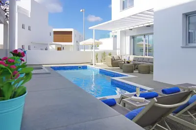 a villa with a swimming pool and chairs and a house at Villa Paradisia in Ayia Napa
