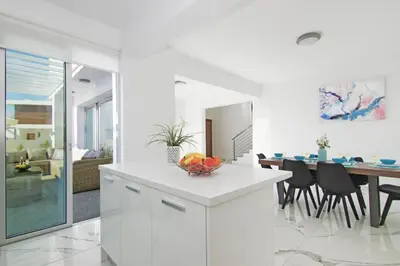 a white kitchen and dining room with a dining table at Villa Paradisia in Ayia Napa