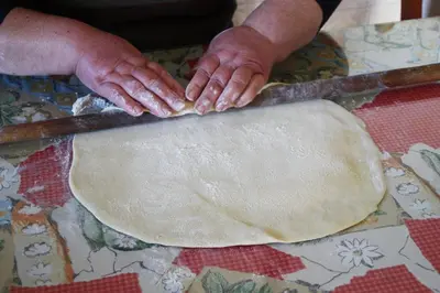 a person making a dough on a table with a knife at Aperanti Agrotourism in Pera Orinis