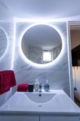 a bathroom with a white sink with a round mirror at Dene Hollow Oroklini in Voroklini