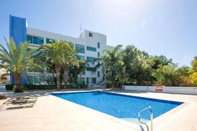 a swimming pool in front of a building at Lucile - Coralli Beachfront Apartment in Paralimni