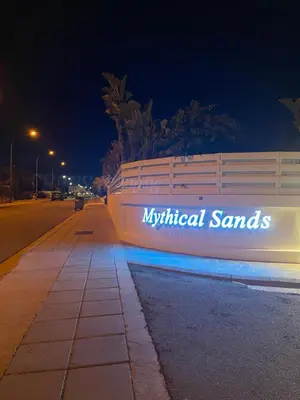 a white fence with the wordsnatural sands on it at night at Mythical Sands Resort - Maria in Protaras