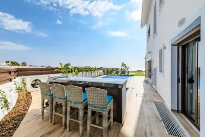 a patio with a table and chairs and a swimming pool at Serenity Seafront Villa in Ayia Napa