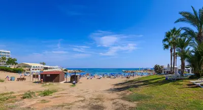 a beach with people sitting on the sand and the ocean at Blue Pelagos Villa in Protaras