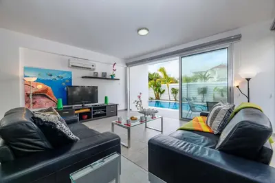 a living room with two black leather couches and a television at Blue Pelagos Villa in Protaras