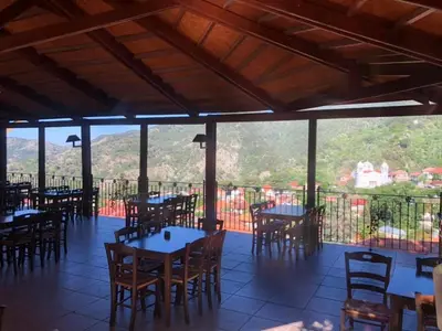 a restaurant with tables and chairs with a view at Mountain Rose Hotel & Restaurant in Pedoulas