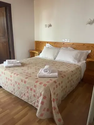 a bedroom with a bed with two towels on it at Mountain Rose Hotel & Restaurant in Pedoulas