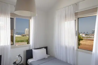 a bedroom with white curtains and a bed and a window at Tonia Seaview Villas in Protaras