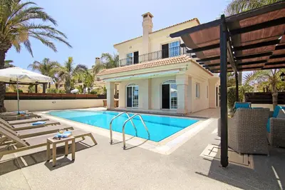 a villa with a swimming pool in front of a house at Villa Oceania - Beachfront in Paralimni
