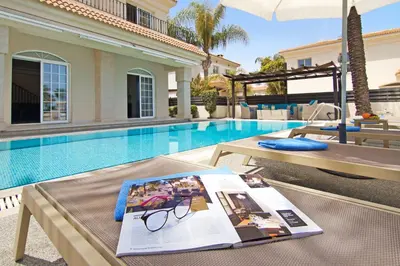 a book on a table next to a swimming pool at Villa Oceania - Beachfront in Paralimni