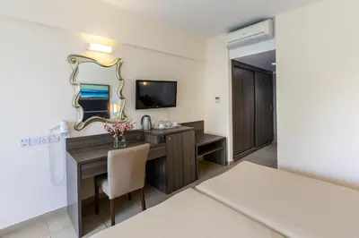 a hotel room with a desk and a mirror at Tofinis Hotel in Ayia Napa