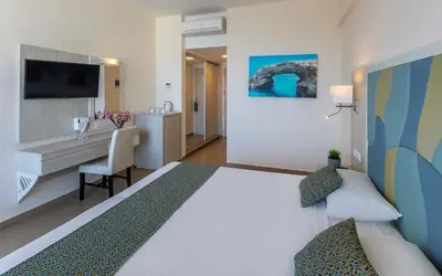 a hotel room with a large bed and a desk at Tofinis Hotel in Ayia Napa