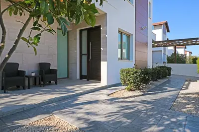 a patio of a house with chairs and a tree at Villa Apollonia in Paralimni