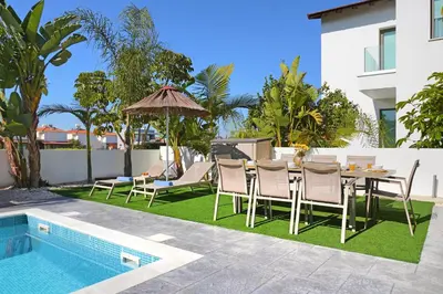 a patio with a table and chairs next to a pool at Villa Apollonia in Paralimni