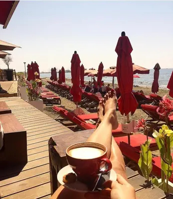 a person laying on the beach with a cup of coffee at Modern 2 bedroom Beach Apartment in Limassol