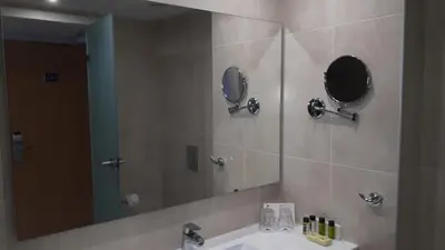 a bathroom with a sink and a large mirror at Karousos Beach Rooms in Ayia Napa