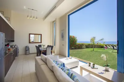 a living room with a couch and a view of the ocean at Protaras Seafront Villa Infinte Aretousa in Protaras