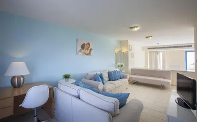 a living room with two couches and a tv at Protaras Seafront Villa Infinte Aretousa in Protaras