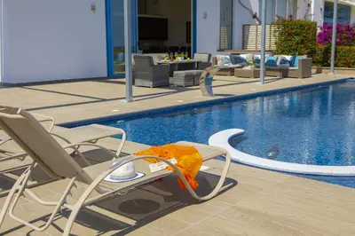 a swimming pool with chairs and a swimming pool at Protaras Seafront Villa Infinte Aretousa in Protaras