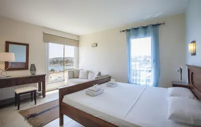 a bedroom with a large bed and a living room at Protaras Seafront Villa Infinte Aretousa in Protaras